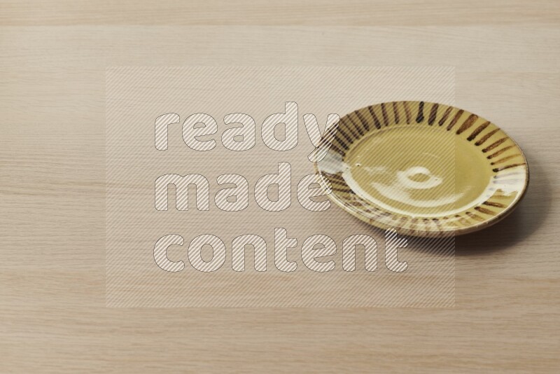 A multicolored pottery plate on light wooden background