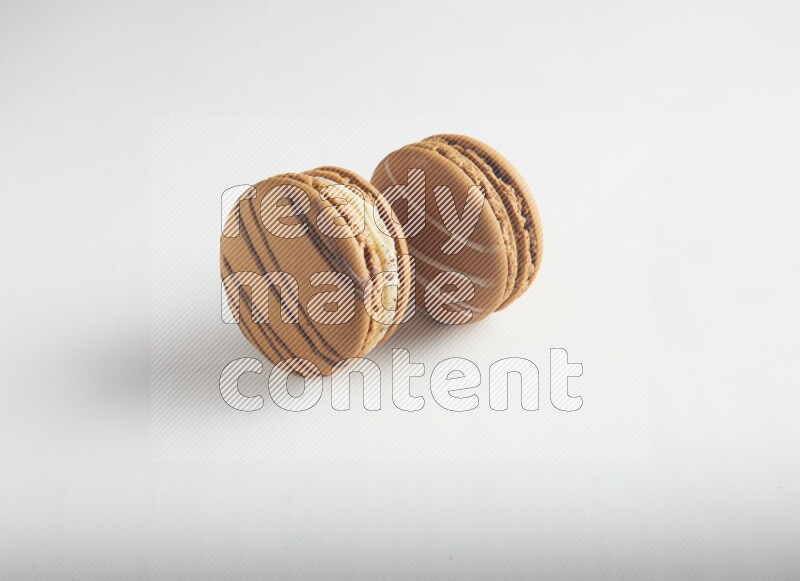 45º Shot of of two assorted Brown Irish Cream, and light brown  Almond Cream macarons on white background