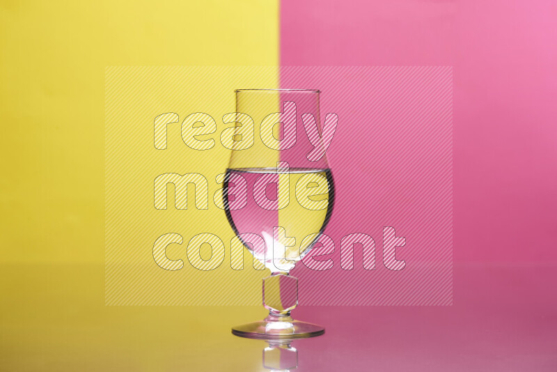 The image features a clear glassware filled with water, set against yellow and pink background