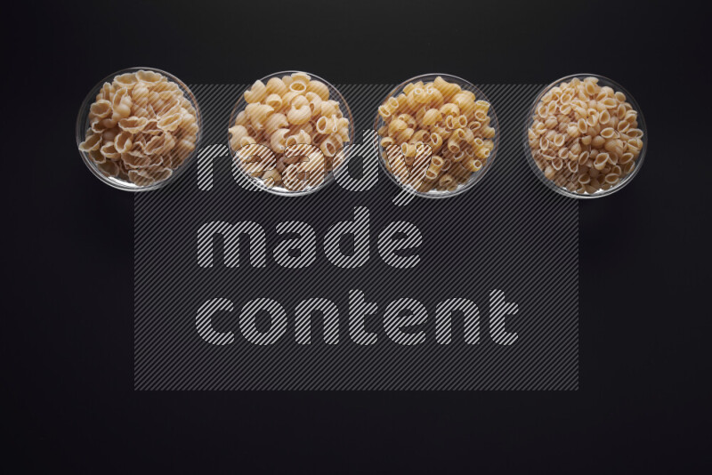 أنواع مختلفة من المعكرونة في وعاء زجاجي علي خلفية سوداء