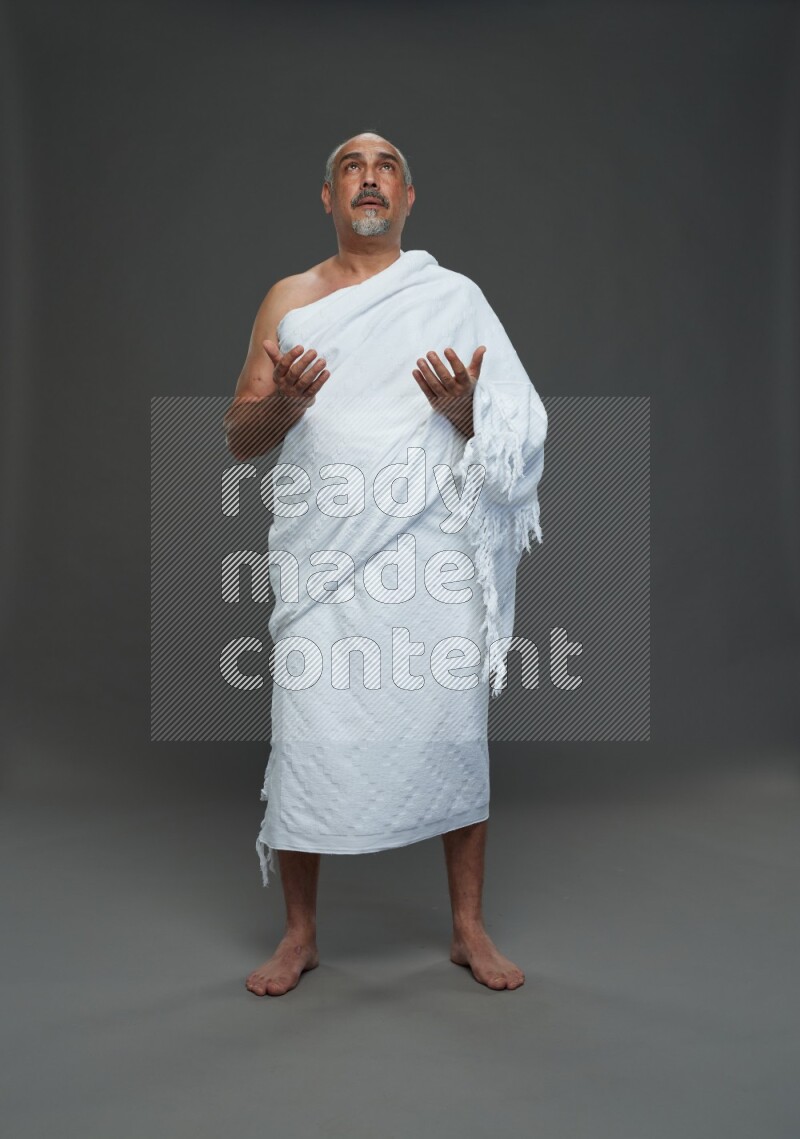 A man wearing Ehram Standing dua'a on gray background