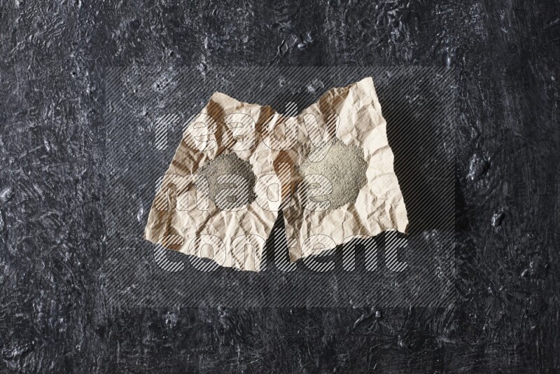 قطعتان من الورق ممتلئتان ببودرة الفلفل الأسود والأبيض على أرضية سوداء