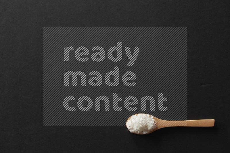 الفلفل الأبيض والقرنفل والهيل والملح والفلفل الأسود وريحان مجفف في معالق خشبية علي خلفية سوداء