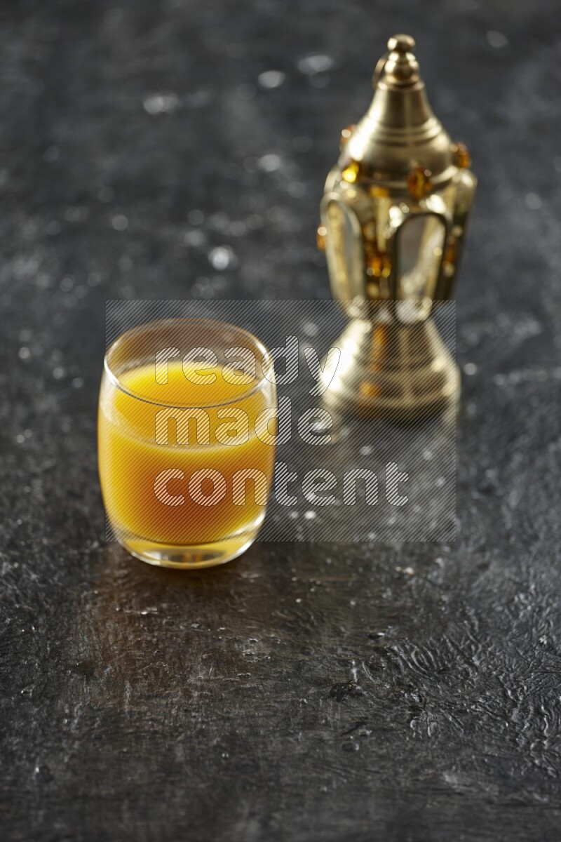 A golden lantern with different drinks, dates, nuts, prayer beads and quran on textured black background