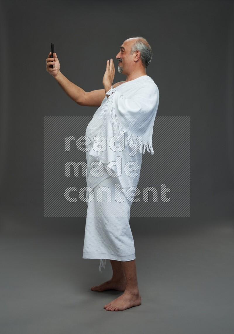 A man wearing Ehram Standing taking selfie on gray background