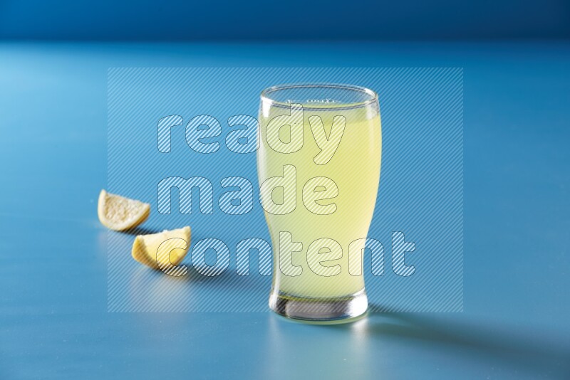 glass of lemon juice on blue background