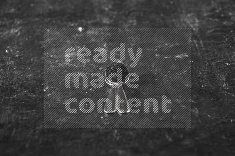 2 metal spoons full of black seeds on a textured black flooring