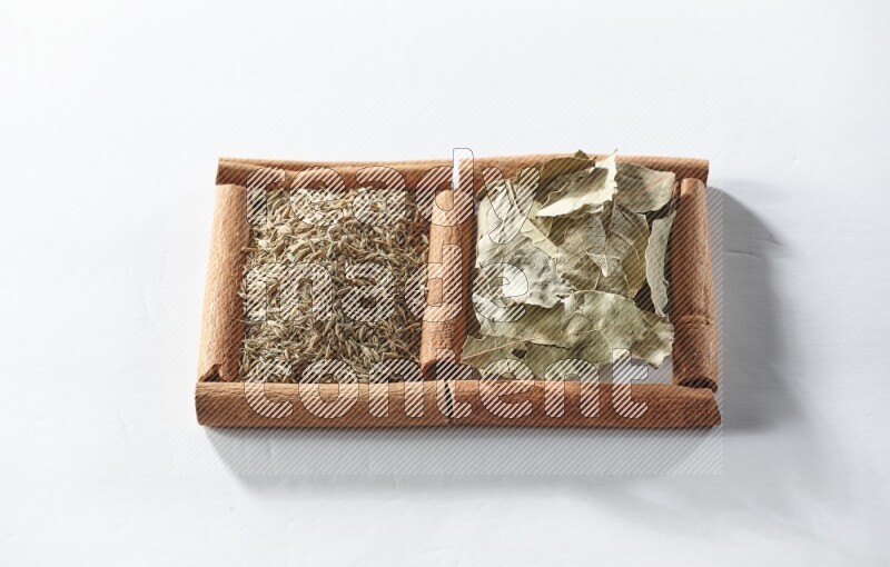 2 squares of cinnamon sticks full of bay laurel leaves and cumin on white flooring