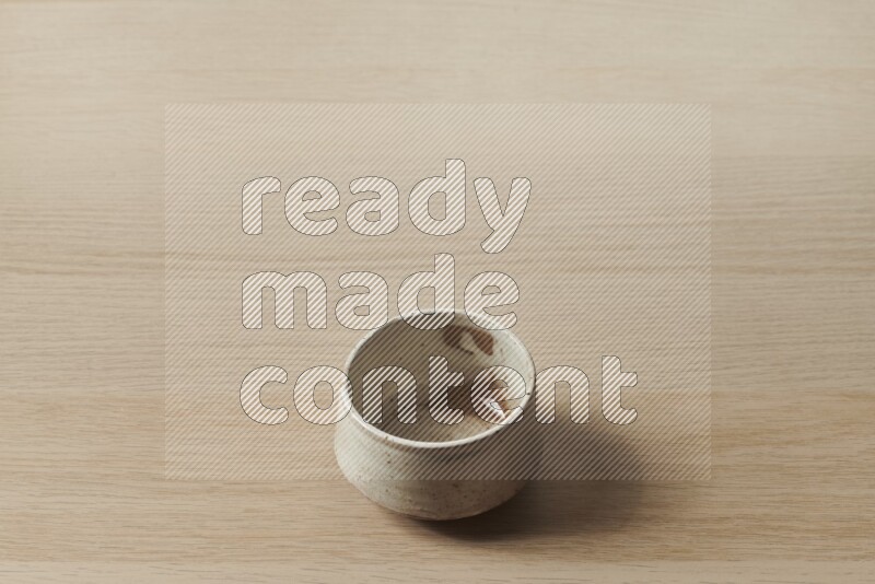 A beige pottery bowl on light wooden background