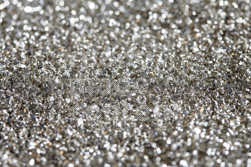 Silver shimmering fragments of glass scattered on a black background