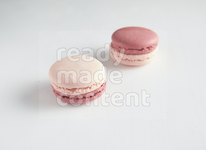 45º Shot of two Pink Litchi Raspberry macarons on white background
