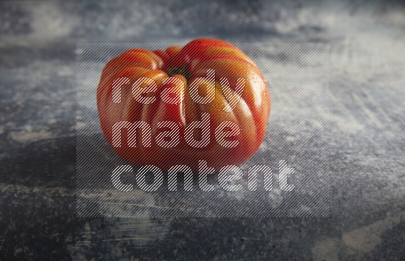 45 degree single heirloom tomato on a textured rustic blue background