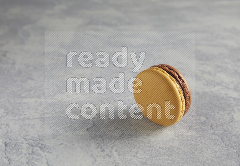 45º Shot of Yellow and Brown Chai Latte macaron on white  marble background