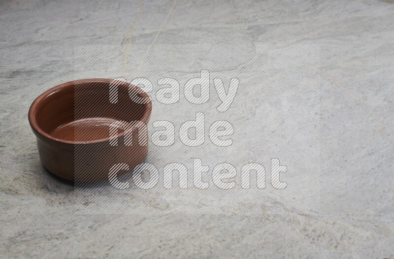 A brown pottery bowl on grey marble background