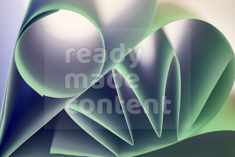 An artistic display of paper folds creating a harmonious blend of geometric shapes, highlighted by soft lighting in green tones