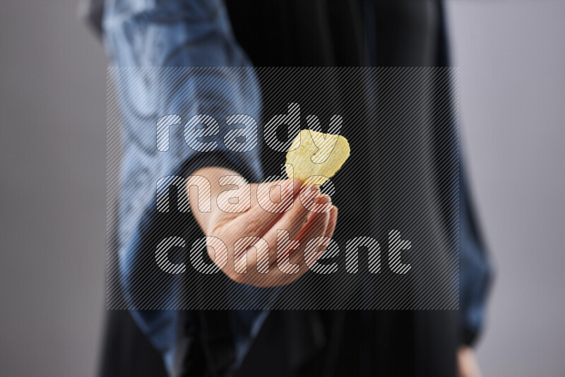 Woman in abaya holding different kinds of snacks in different positions