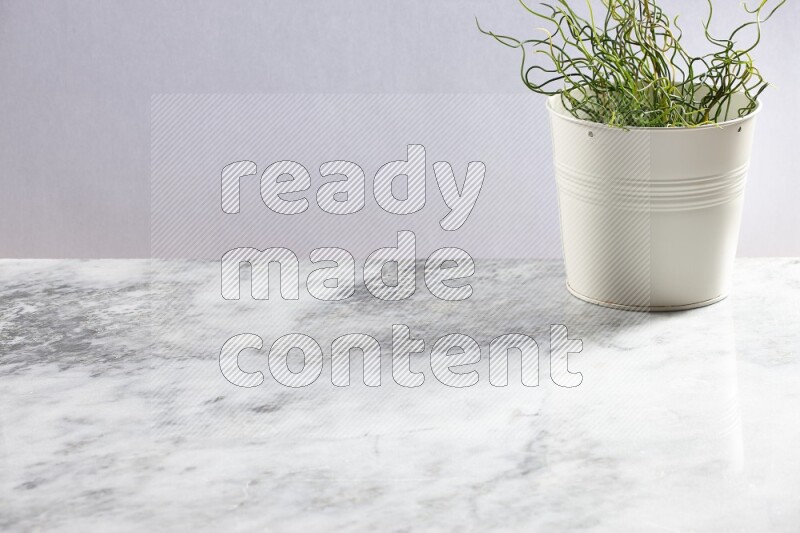 Green artificial plant in white pot on light grey marble background
