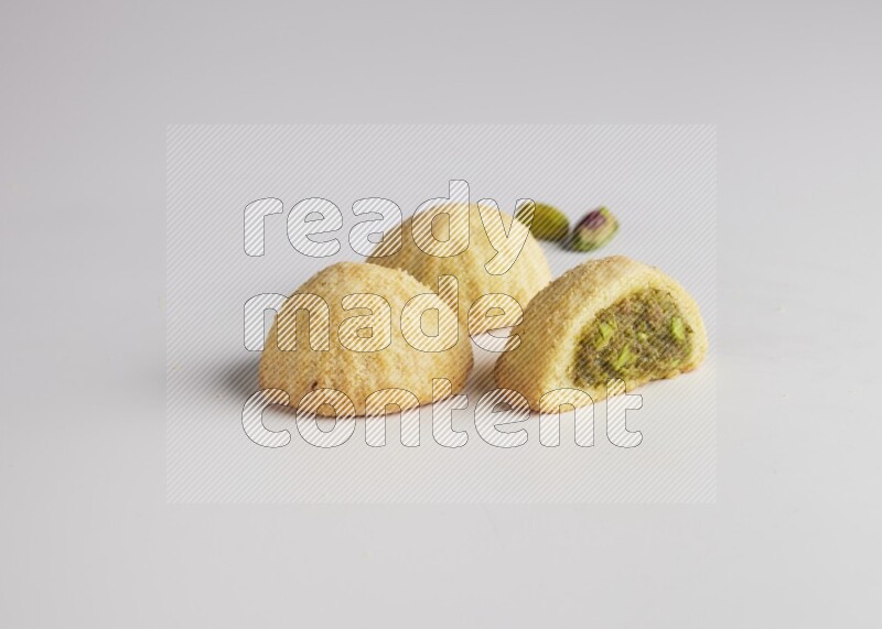 Three Pieces of Maamoul filled with pistachio paste  one of them is cut direct on white background