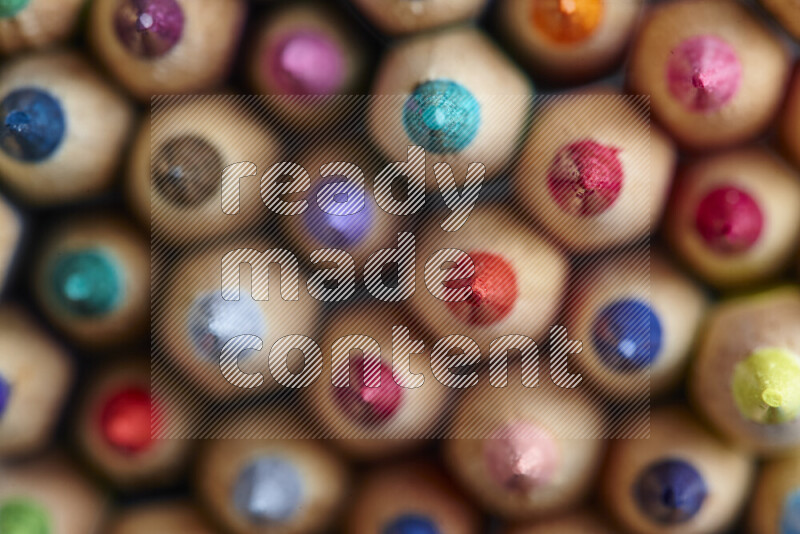 The image captures top view shot of sharpened colored pencils on grey background