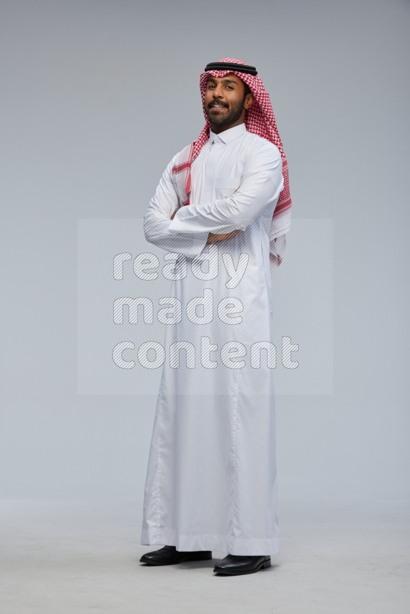 Saudi man Wearing Thob and shomag standing with crossed arms on Gray background