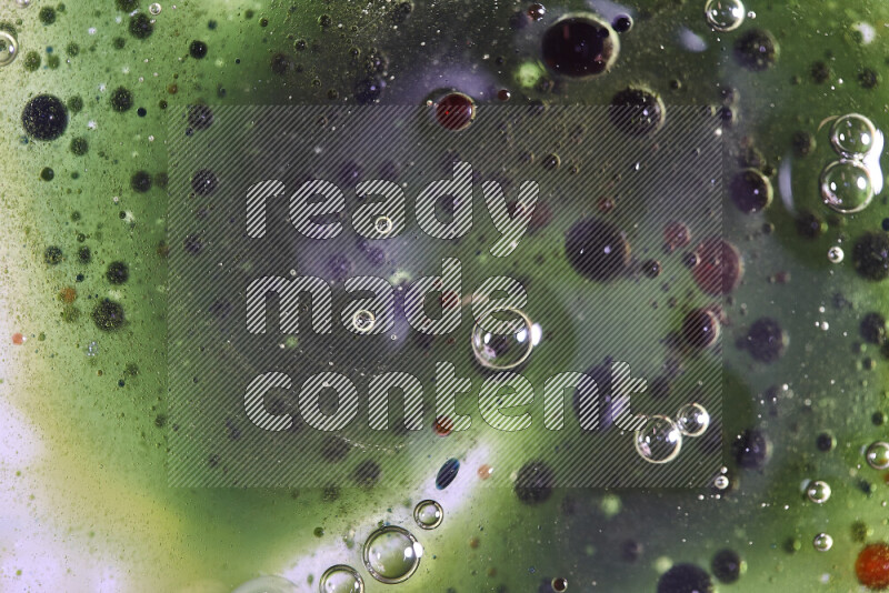 Close-ups of abstract red, green and blue watercolor drops on oil Surface on green background