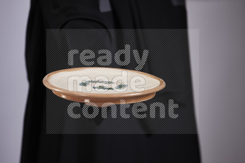 امرأة ترتدي عباءة سوداء تحمل أدوات فخارية مختلفة في أوضاع متعددة