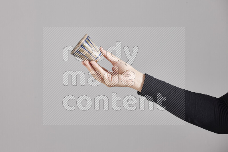 A woman in black abaya holding different pottery essentials in different positions