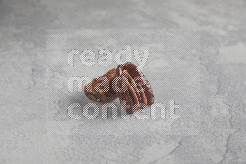 TWO pecan stuffed dates on alight grey background
