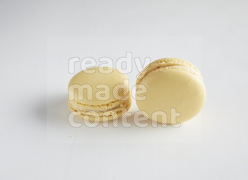 45º Shot of two Yellow Vanilla macarons on white background