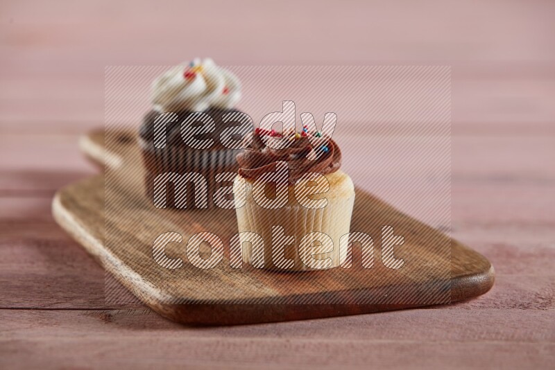 Vanilla mini cupcake topped with chocolate cream on a wooden board