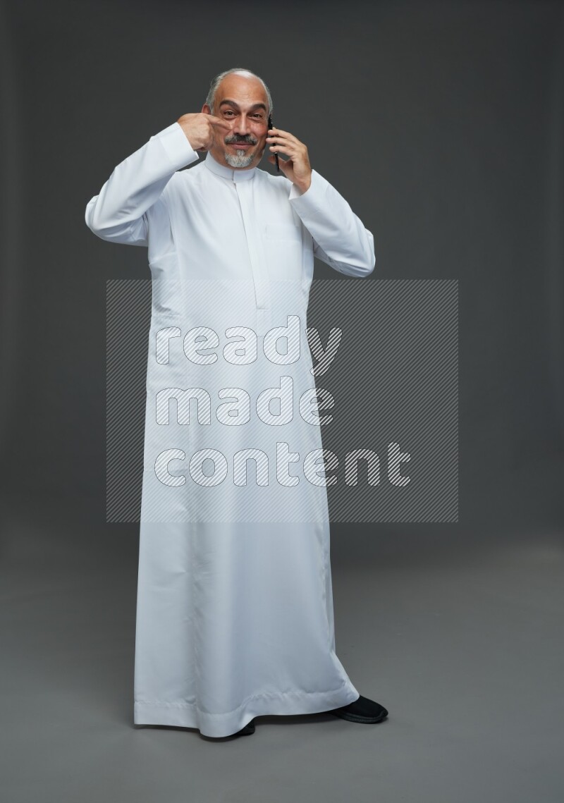 Saudi man without shomag Standing talking on phone on gray background