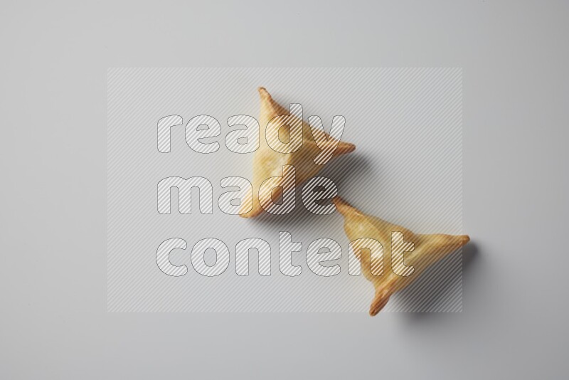 Two fried sambosa from a top angle on a white background