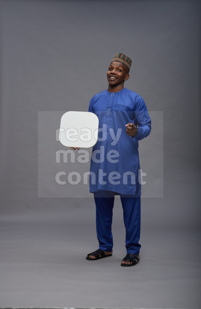 Man wearing Nigerian outfit standing holding social media sign on gray background