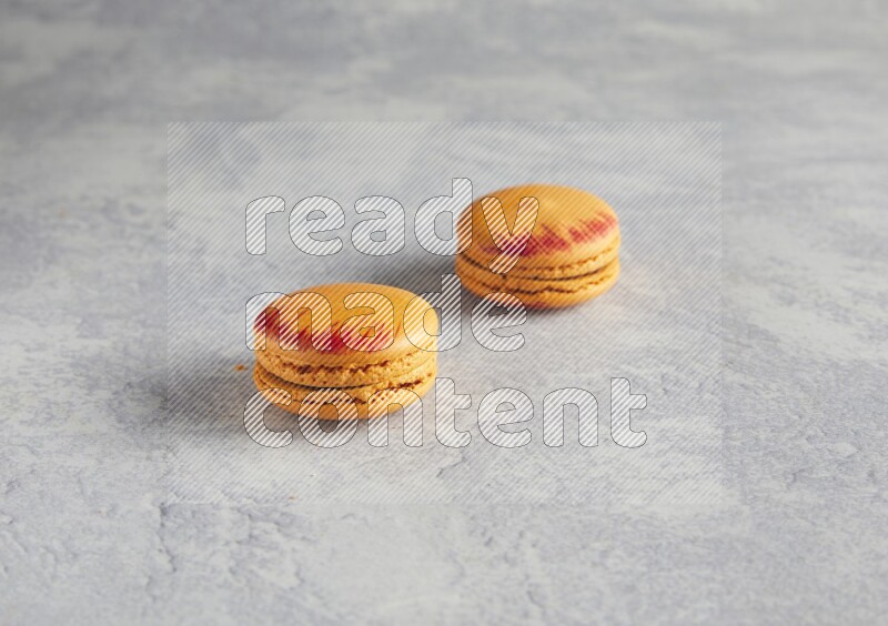 45º Shot of two orange Exotic macarons on white  marble background