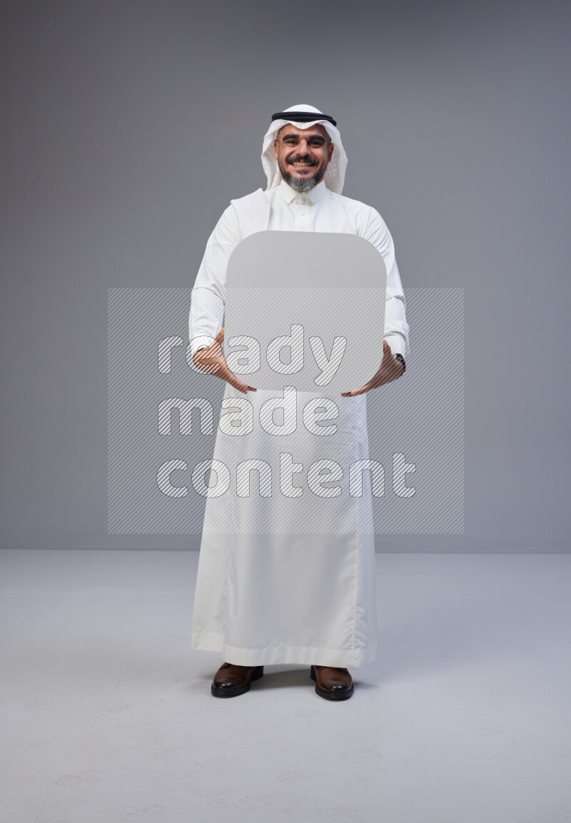 Saudi man Wearing Thob and white Shomag standing holding social media sign on Gray background