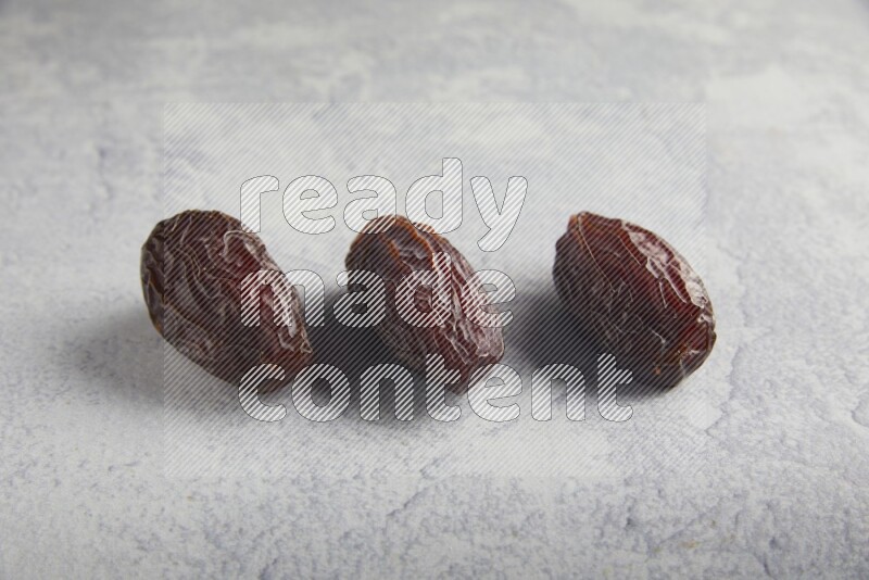 three madjoul dates on a light grey background