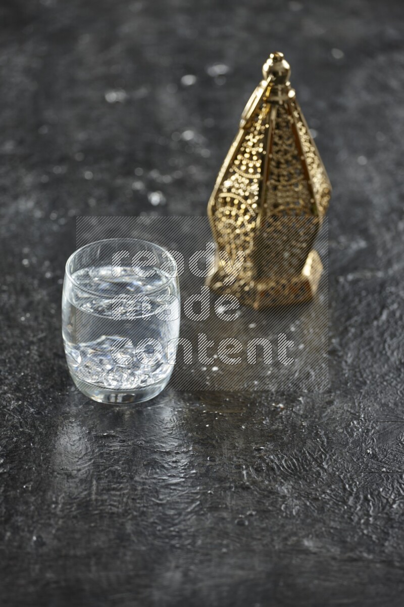 A golden lantern with different drinks, dates, nuts, prayer beads and quran on textured black background
