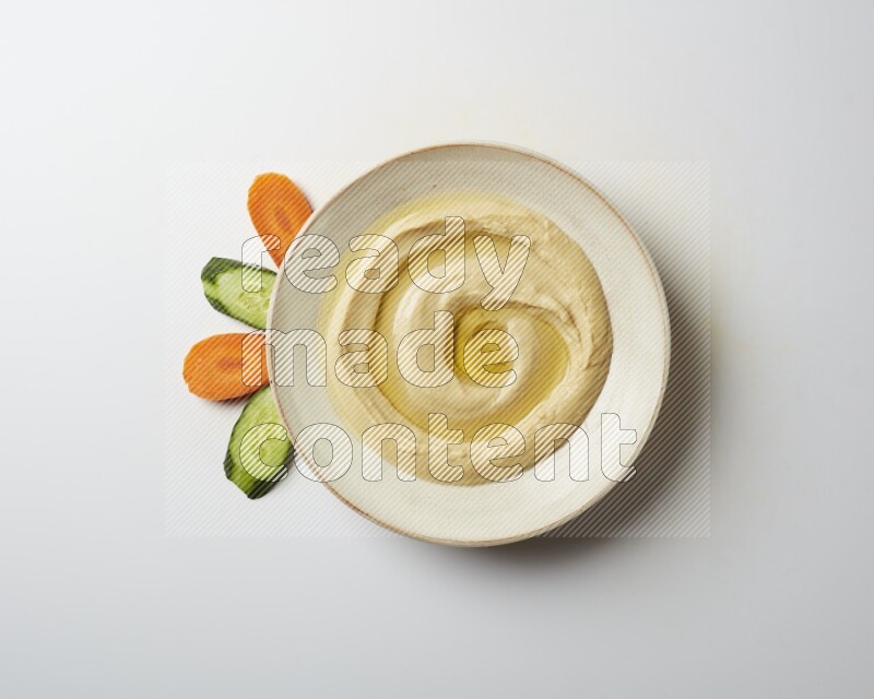 Hummus in a pottry plate garnished with olive oil on a white background