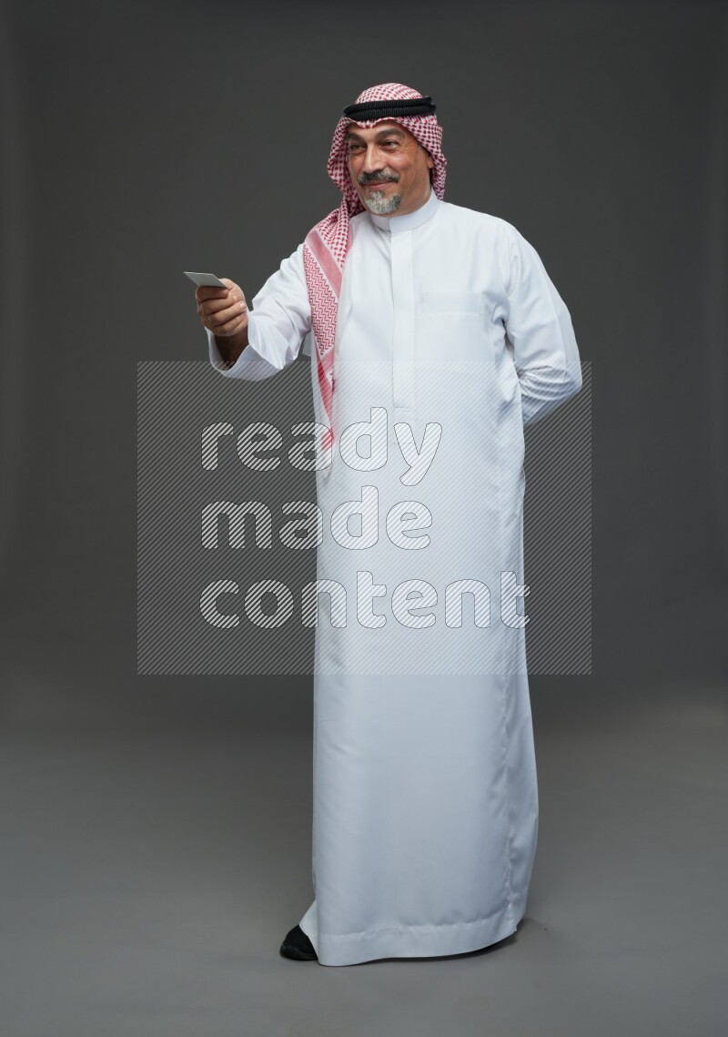 Saudi man with shomag Standing holding ATM card on gray background