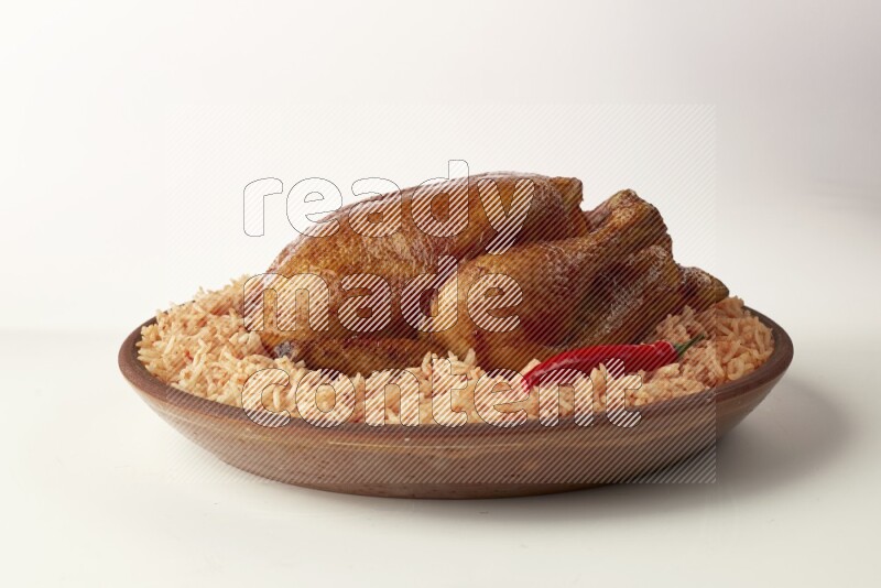 red basmati Rice with whole roasted chicken on a pottery plate direct on white background