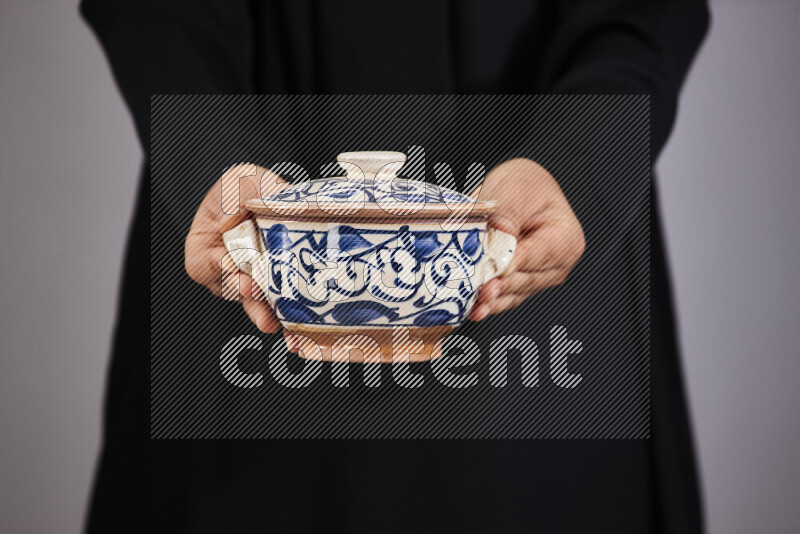 A woman in black abaya holding different pottery essentials in different positions