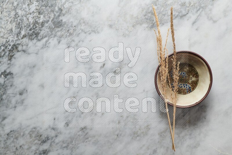 Wheat stalks on decorative pottery plate on grey marble background