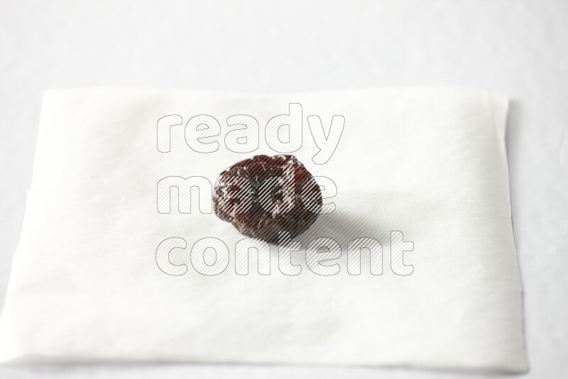 A dried plum on a piece of paper on a white background in different angles