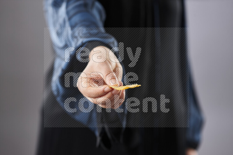 Woman in abaya holding different kinds of snacks in different positions