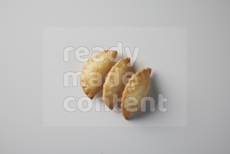 Three fried sambosa from a top angle on a white background