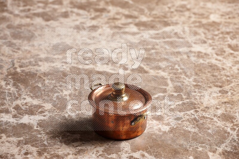 A small copper pot on beige marble background