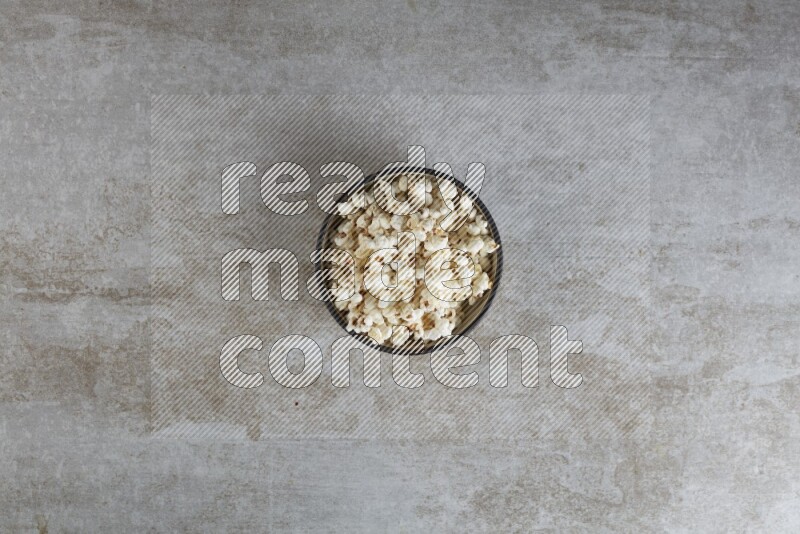 popcorn in a multi-colored pottery bowl on a grey textured countertop