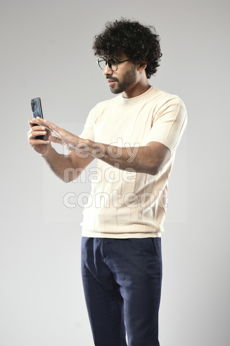 A man wearing casual standing and shooting with his phone on white background