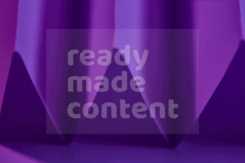 صورة مجردة مقربة تظهر طيات ورقية هندسية حادة بتدرجات اللون الارجواني