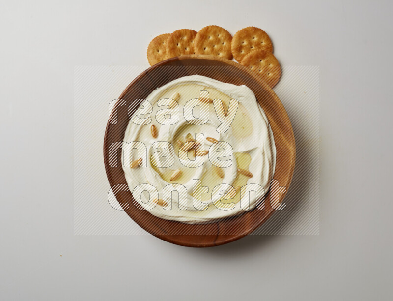 Lebnah garnished with pine nuts in a wooden plate on a white background